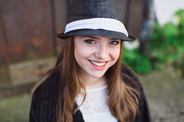 Portrait of a stylish and beautiful teenager girl in the hat. She posing and smiling.