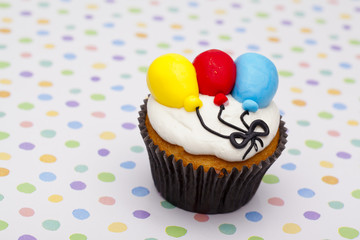 cupcake with balloon design over polka dots background.