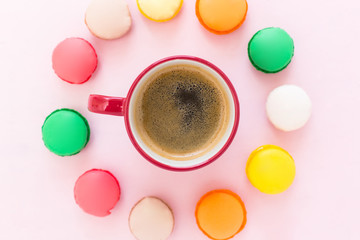 Coffe cup and colorful macaroons on pastel background, top view