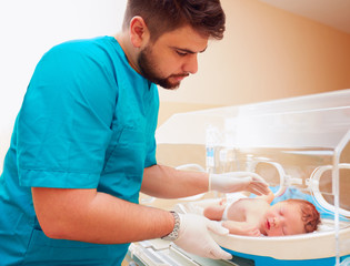 young adult man taking care of newborn baby in infant incubator