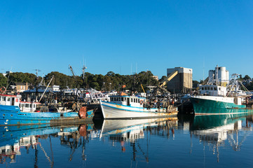 Fototapeta na wymiar Fishing boats, trailers at port at day against clear blue sky on the background