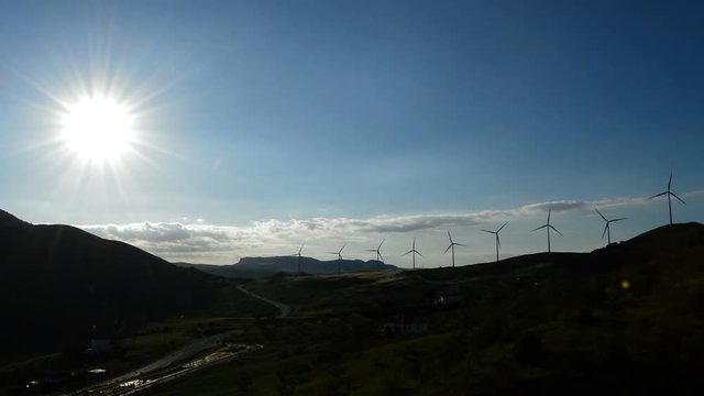 Wind towers energy in the mountains at sunset backlit