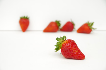 Red strawberries with green stems arranged in white background