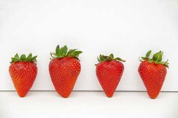 Red strawberries with green stems arranged in white background