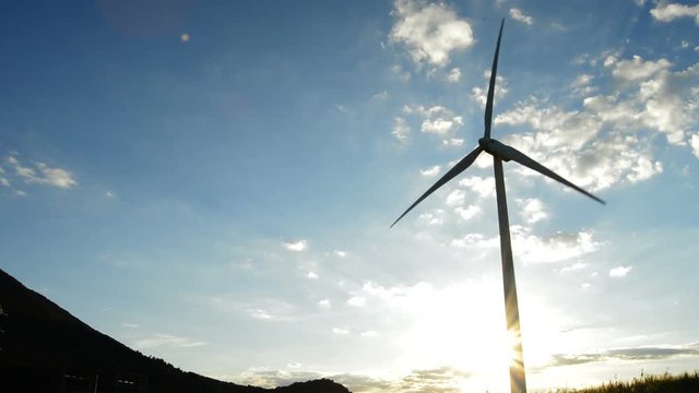 Wind turbine moving at field at sunset