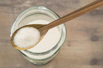 Granulated sugar in glass jars and wooden spoon