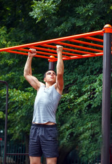 Obraz premium Muscular man doing pull-ups on horizontal bar