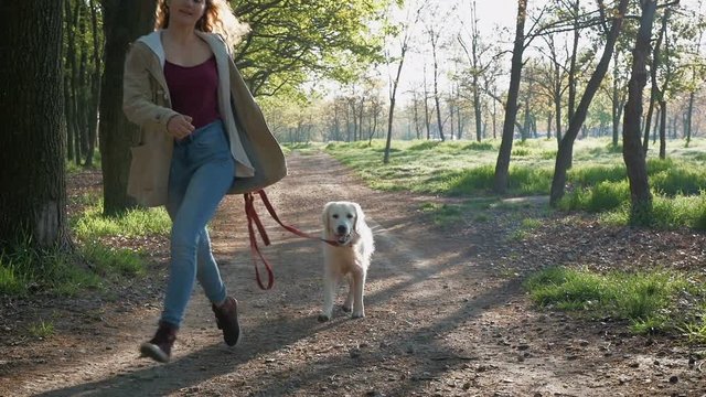Girl running with dog in park, slow motion