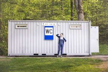 Woman keeping her nose with two fingers at a public toilet in th