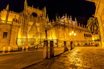 Fototapeta na wymiar Side view of Cathedral of Seville illuminated by night, the world's largest Gothic Cathedral and the third religious building to size, Andalucia, Spain.