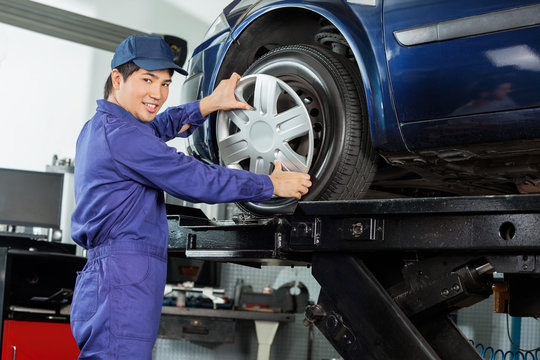 Confident Mechanic Fixing Hubcap To Car Tire