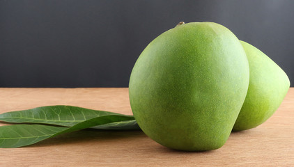 Two raw organic mangoes on a wooden board.
