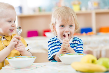Kid eating in kindergarten and showing thumbs up