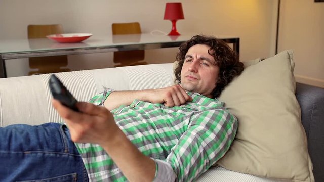 Unhappy man lying on the sofa and stop watching television
