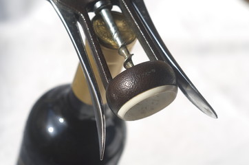 A bottle of wine and a  sommelier corkscrew