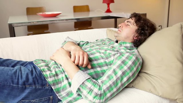 Man sleeping on the sofa and being waken up by smartphone
