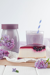 Black currant cheesecake slice near bilberry milkshake and lilac