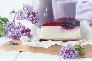 Black current cheesecake slice near lilac flowers