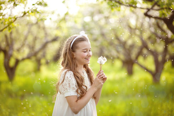 Girl blowing on a dandelion in the garden