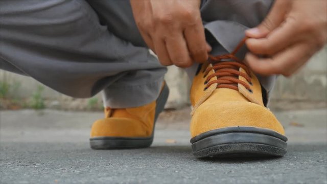 Close up of The man siting to wears safety shoes on street