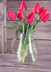 Red fresh tulip bouquet on a dark wooden planks