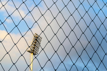 Black soccer net with blue sky and spotlight pole background