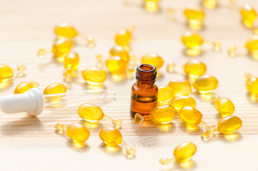 gold capsules of natural cosmetik for face, 1 ml bottle with essential oil and a pipette on the wooden