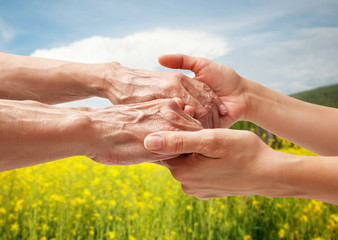 Hands of an elderly senior holding the hand of a woman