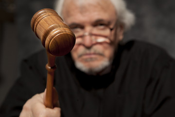 Old male judge in a courtroom striking the gavel