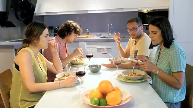 Friends eating dinner and quarrel with each other at the table
