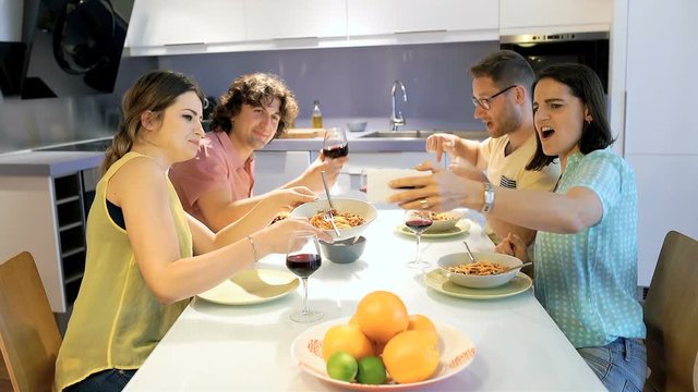 Happy Friends Having A Videocall While Eating Dinner Together
