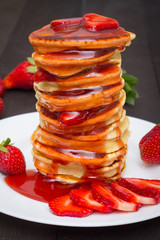 Fresh pancake stack with syrup streaks decorated with strawberries