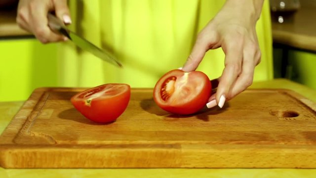 Woman slicing tomato. Female hands cut red tomato slices. Big knife. In the kitchen. Wooden board. house-proud woman. Fresh tomatoes. Fresh vegetables. sharp knife.