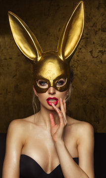 Beautiful blonde young woman in carnival gold rabbit mask with long ears