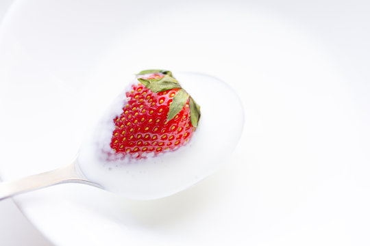 Red strawberries in cream on a spoon