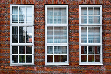 Three tall, white painted, wood windows in a red masonry brick facade