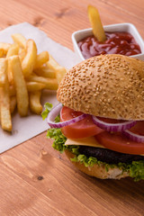 homemade hamburger on wooden table with fries