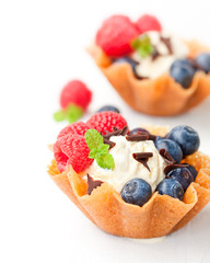 brandy  snaps baskets with ice cream and berries on white backgr