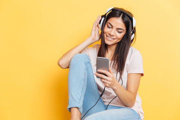 Woman listening music in headphones and using smartphone