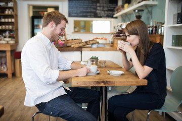  Young Couple Sitting At Table In Coffee Shop Together	