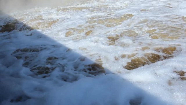 splashing waterfall and a strong swirling water with foam on Plotinka Yekaterinburg summer