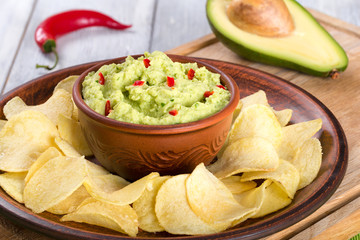 bowl of guacamole dip and potato chips