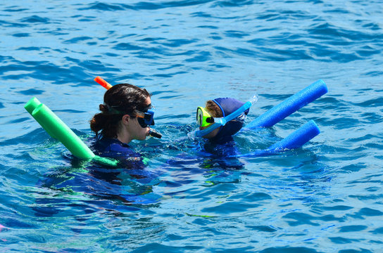 Woman instructor teach little girl how to snorkelling dive