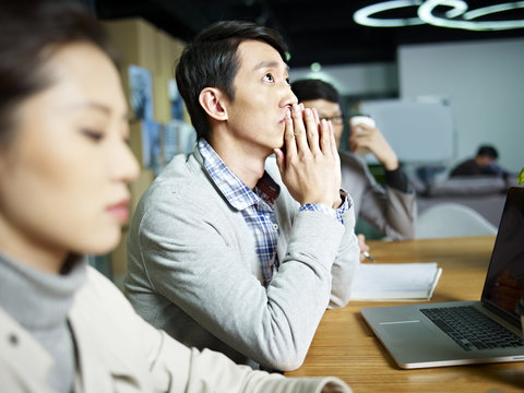 Young Asian Businessman Thinking During Meeting