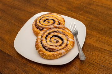 Two Cinnamon Rolls on White Plate with Fork