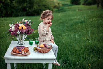 Little baby girl eats chocolate cake in nature at a picnic. The concept of a happy childhood