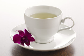 cup of herbal tea with saucer and flower