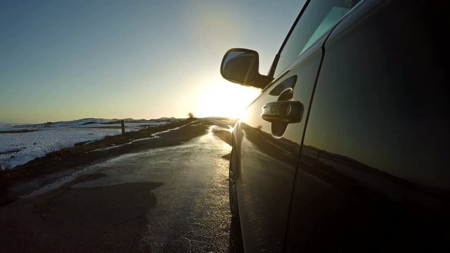 Driving on muddy road with luxury car during gorgeous sunset