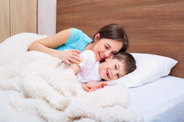 Mom and son playing on the bed.