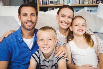 Portrait of happy family sitting by sofa